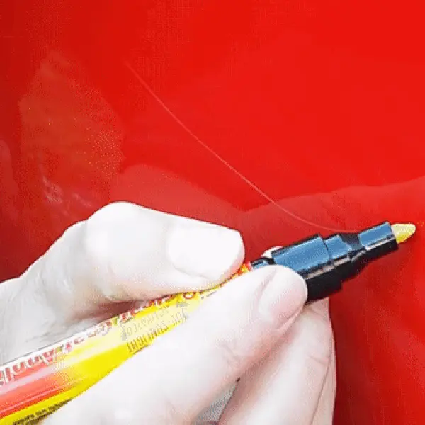 man using carscratcher pencil to cover a scratch