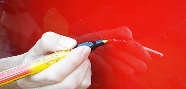 car scratch pencil in use in red car